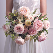 Bride holding a bouquet of Keira roses - Frilly wedding-dress petals frame her cupped blooms in every shade of soft pink, from raspberry ripple to clotted cream. 
