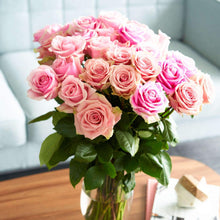 vase of pink bi colored roses with ruffled edges and light pink cream tones with darker pink on the outer petals 

