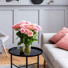 vase of pink bi colored roses with ruffled edges and light pink cream tones with darker pink on the outer petals 
